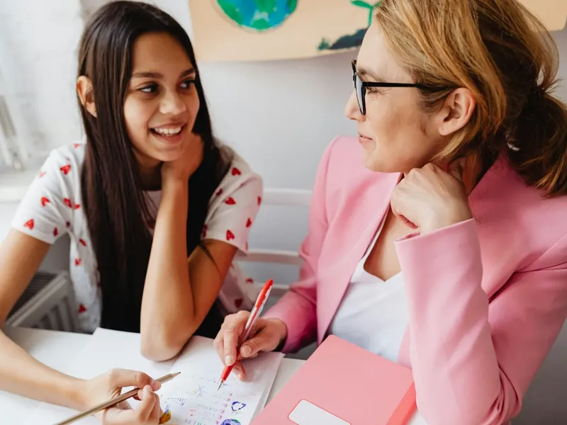 A tutor and student reviewing schoolwork together at a desk