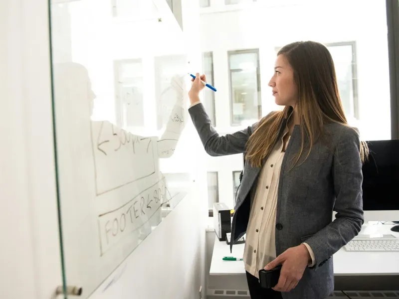 A tutor preparing lesson notes on a whiteboard